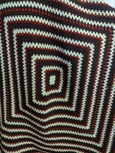 a crocheted blanket that is made to look like a spiral design with red, white and black stripes