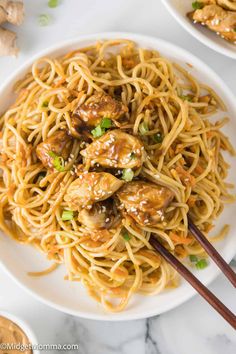 two plates of noodles with meatballs and chopsticks next to them on a marble table