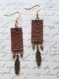 Another southwestern creation! These rectangle floral embossed brown leather earrings are fabolous. The earrings have dangling metal feather and wooden round beads. The earrings are created on gold tone precious metals. The earrings are light weight and a great gifting idea for teens and older.  Length: 3.25 inches Width: 5/8 of an inch Purchases will be shipped within 3-5 business days, unless requested otherwise. Packages are shipped via USPS first-class mail. Once your order has been transpor Bohemian Hand-tooled Leather Earrings, Hand Tooled Leather Drop Earrings, Brown Hand Tooled Dangle Earrings, Hand Tooled Brown Dangle Earrings, Brown Hand Tooled Drop Earrings, Artisan Brown Hand Tooled Earrings, Brown Bohemian Concho Earrings, Brown Leather Dangle Earrings, Bohemian Leather Drop Earrings