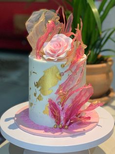 a white cake with pink and gold decorations on it's side sitting on a table