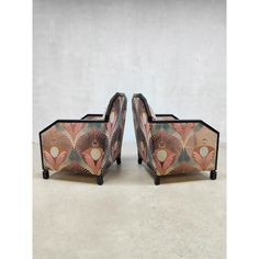 a pair of art deco style chairs with floral designs on the back and arms, facing each other