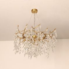 a chandelier hanging from the ceiling with clear crystal beads and gold leaf accents