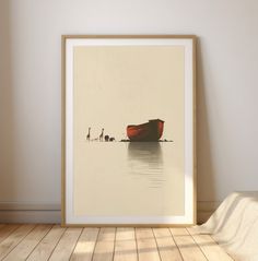 a red boat sitting on top of a wooden floor next to a wall with a white frame