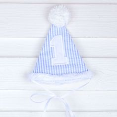 Happy 1st birthday to your little one! This cone hat with a pom pom on top is perfect for cake smashing pictures and first birthday celebrations. Your little one will look so adorable in this darling hat styled to match their big day! Cute White Hat For First Birthday, Playful Blue Hat For First Birthday, Playful White Party Supplies For First Birthday, Playful White Hat For First Birthday, Playful White Hat For Birthday, Playful White Hats For Birthday, Playful White Birthday Hat, First Birthday Hat, Cone Hat