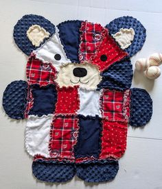 a teddy bear made out of quilts on the floor next to baseballs and balls