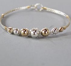 a gold and silver beaded bracelet on a gray surface