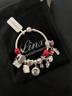 a charm bracelet with charms on it sitting on top of a black velvet bag,