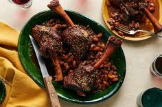 two plates filled with meat and beans on top of a table