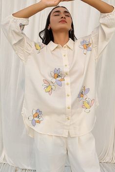 White boxy fit shirt with hand appliqued multicolor flowers embroidery. Components: 1 Pattern: Embroidered Type Of Work: Applique Neckline: Shirt collar Sleeve Type: Three quarter Fabric: 100% organic cotton made with soyabean fibres Color: White Other Details:  Elasticated detailing on sleeve hem Button placket Note: The pant worn by the model is not for sale Occasion: Work - Aza Fashions Linen Tops, Embroidered Midi Dress, Simple Embroidery, Fashionista Clothes, Upcycled Fashion, Indian Fashion Dresses, Flower Applique, Women Shirts Blouse, Linen Women