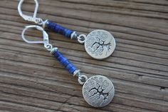 Inspired by nature, these blue dangle boho earrings are made with lapis lazuli stones, antique silver plated round charms featuring a tree of life. They hang from sterling silver lever backs. These earrings are light, comfortable and easy to wear everyday. They combine simplicity and charm to fit any casual or formal event. Color : Lapis Lazuli rondelle stones Finish : Sterling Silver lever back, Sterling Silver head pins, Antique Silver Round Tree Charms ( Lead and Nickel Free ). Length: 2-1/4 Nature-inspired Blue Dangle Earrings, Bohemian Blue Hypoallergenic Jewelry, Lapis Earrings Silver, Dark Blue Earrings, Tree Charms, Earrings Nature, Lapis Earrings, Lapis Lazuli Earrings, Casual Earrings