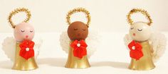 three little angel figurines with red bows on their heads, one in gold and the other in white