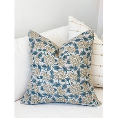 a blue and white pillow sitting on top of a couch next to two pillows in the shape of flowers