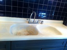 a white sink sitting under a faucet next to a blue tiled counter top