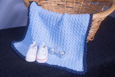 a pair of white tennis shoes sitting on top of a blue blanket next to a basket