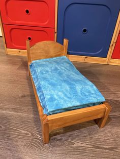 a small wooden bed sitting on top of a hard wood floor next to colorful dressers