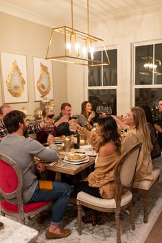 a group of people sitting around a dining room table eating food and drinking wine together