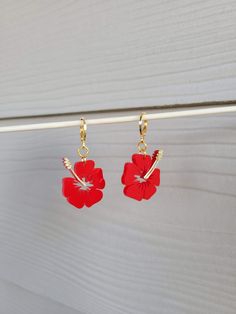 two red flowers hanging from hooks on a white door handle with gold chain attached to it