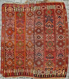 two old rugs sitting on top of a stone wall