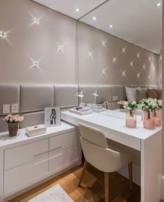 a white desk with flowers and vases on it in front of a large mirror