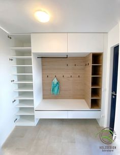 an empty room with white shelving and blue coat hanging on the door knobs