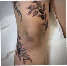 a woman's leg with flowers and leaves tattoo on the side of her thigh