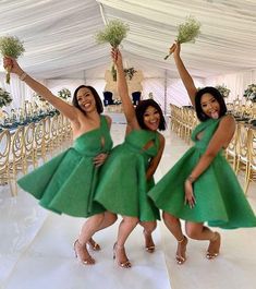 three women in green dresses holding flowers and posing for the camera with their arms up