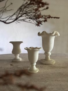 three white vases sitting on top of a table