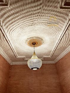 a light fixture hanging from the ceiling in a room with brown walls and tile flooring