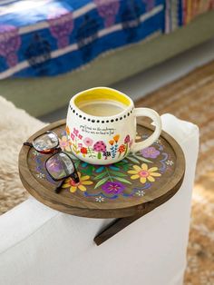 a tray with a cup and sunglasses on it sitting on a chair next to a bed