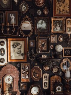 a wall covered in lots of different types of framed pictures and clock faces on it's sides