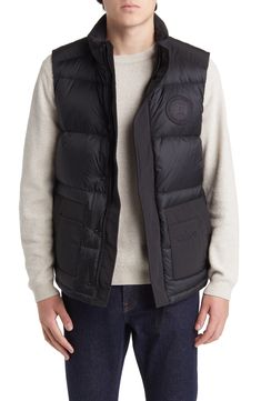 Weather it all in comfort and warmth wearing this vest featuring dual-entry pockets, a webbing grab strap at the upper back and 625-fill-power down insulation. 28" length (size Medium) Storm placket Stand collar Durable water-repellent (DWR) finish Lined, with 625-fill-power down 100% polyamide with 84% polyester, 16% cotton contrast Dry clean Made in Canada Functional Black Vest Outerwear, Functional Black Outerwear Vest, Functional Black Vest With Padded Collar, Black Functional Vest With Padded Collar, Quilted Black Nylon Vest, Black Quilted Nylon Vest, Sleeveless Black Down Outerwear, Black Sleeveless Vest With Padded Collar, Black Quilted Outdoor Vest