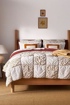 a bed with white and red comforters in a bedroom next to a lamp on a table