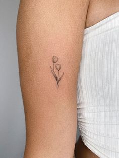 a woman's arm with a small flower tattoo on the left side of her body