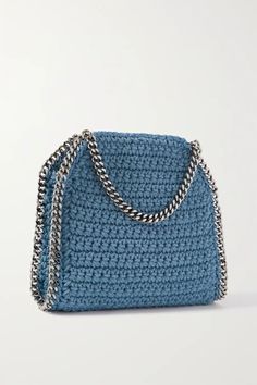 a blue handbag on a white surface with a chain hanging from the front and side