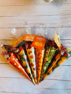 seven orange and yellow candy bags in cellophane wrap on white wood flooring