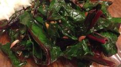 a close up of a plate of food on a wooden table with rice and greens