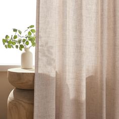 a potted plant sitting on top of a wooden table next to a white curtain