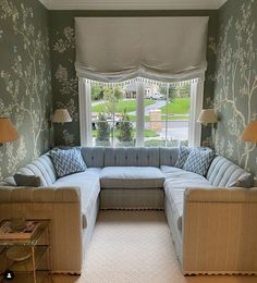 a living room filled with furniture next to a large window covered in windowsills