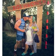 a man and woman kissing in front of a sign