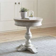 a white table sitting on top of a wooden floor next to a potted plant