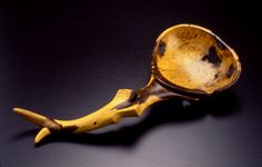 an old wooden spoon sitting on top of a black table next to a banana peel