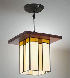 a light fixture hanging from the ceiling with stained glass panels on it's sides