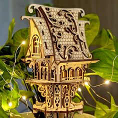 a small wooden house with lights on it's roof sits in front of a potted plant