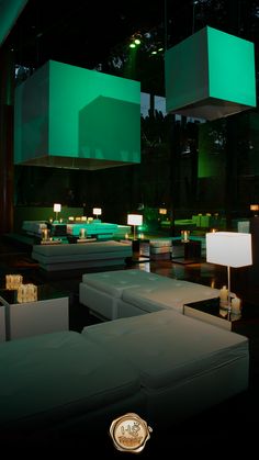 a room filled with lots of white couches next to each other under green lights