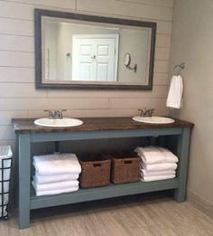 a bathroom with two sinks and towels stacked on the counter next to each other in front of a large mirror