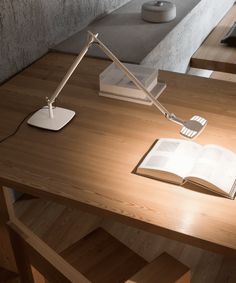 an open book on a desk next to a lamp