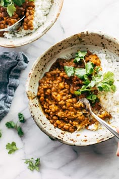 two bowls filled with rice, beans and cilantro