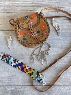 This tiny tooled leather purse has a long shoulder strap and pretty hand-colored flowers.  A souvenir of central Mexico it is fully intact with no loose stitches and in good sturdy condition,  though obviously used and loved.  The strap has an 18 inch drop  and the body of the bag is 4 x 4 x 1 inch Also included with the bag: a pair of silver wing clip on earrings a beaded bracelet a silver-tone wishbone necklace shown on a tiny manaquin. All in good condition and very boho vibe.  I am combining a lot of jewelry and purses for a single price to beat the costs of shipping.  Be sure to look around my shop for more great combos. Multicolor Bohemian Jewelry For Everyday, Multicolor Bohemian Jewelry For Everyday Use, Traditional Handmade Jewelry For Everyday Use, Hand Tooled Bohemian Jewelry For Everyday, Bohemian Hand Tooled Jewelry For Everyday Use, Artisan Hand Tooled Jewelry, Multicolor Hand Tooled Jewelry As Gift, Multicolor Hand Tooled Jewelry Gift, Multicolor Hand Tooled Jewelry For Gifts