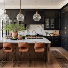 a kitchen with black cabinets, marble counter tops and pendant lights hanging from the ceiling