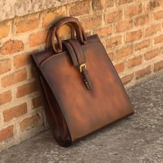 Our briefcase is the key item that every professional needs in order to carry either papers or electronic devices. You can create a unique and personal article to match your wardrobe as well as your profession by combining the different materials available. Its dimensions are 13 x 16.5 x 2 inches / 33 x 42 x 5 cm. THE DETAILS: Materials: cognac burnished painted calf Lining: brown fabric A unique savoir-faireAll our bags & leather goods are handmade in Spain —current artisans for the most recogn Unique Leather Bag, Men Handbags, Leather Work Bag, Designed Shoes, Custom Design Shoes, Hot Style, Vintage Leather Bag, Leather Luggage, Leather Bags Handmade